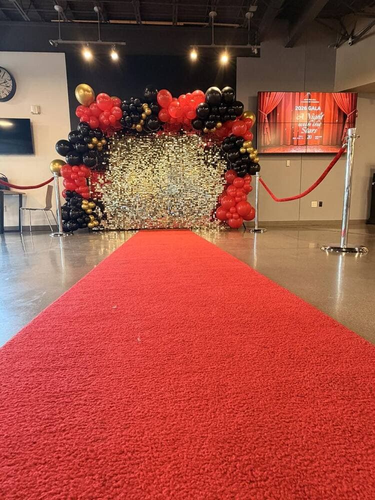 Red carpet and gold-sequin backdrop with black and red balloon garland