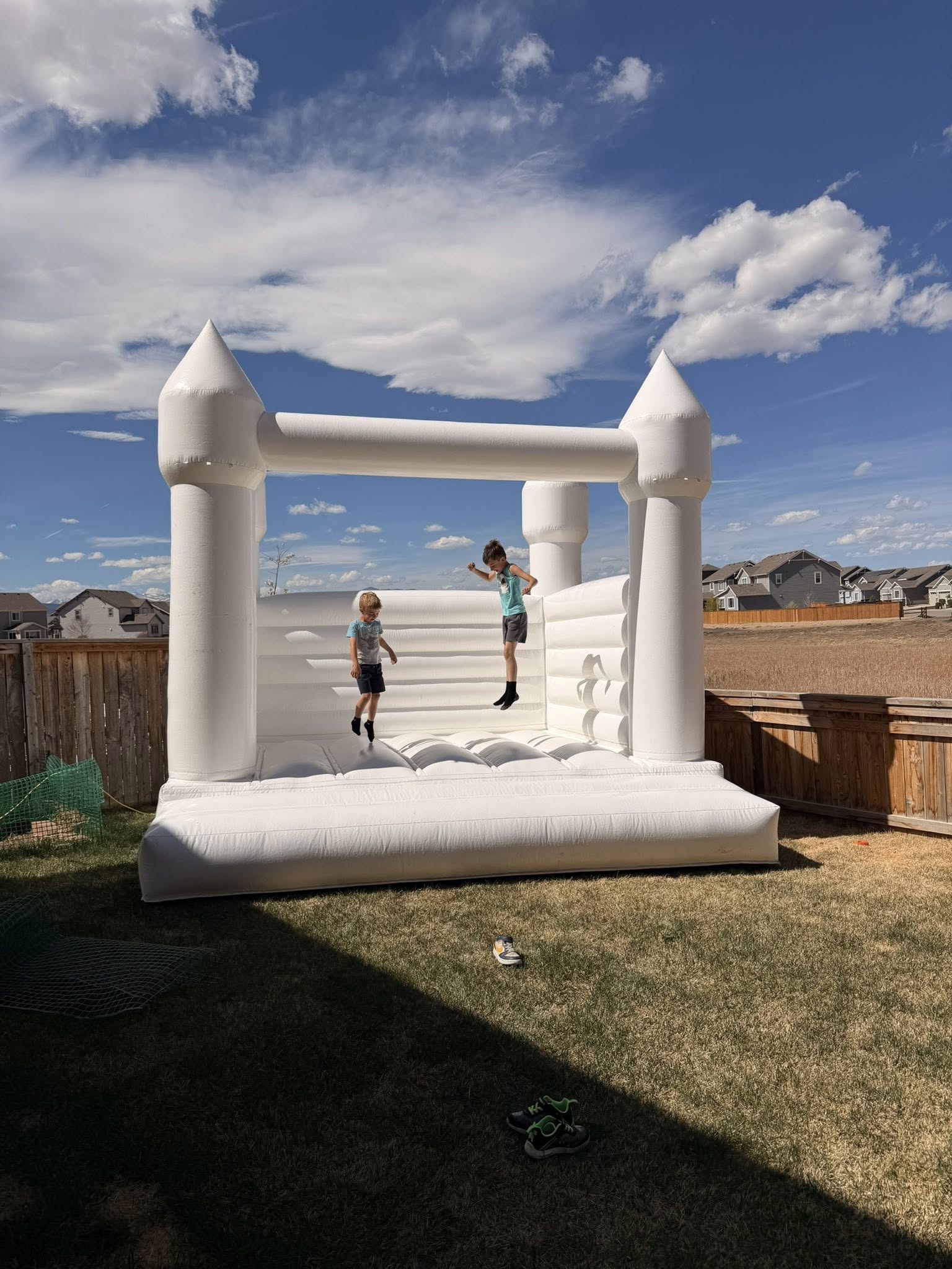 Kids bouncing in a white wedding-style bounce house under Colorado blue sky